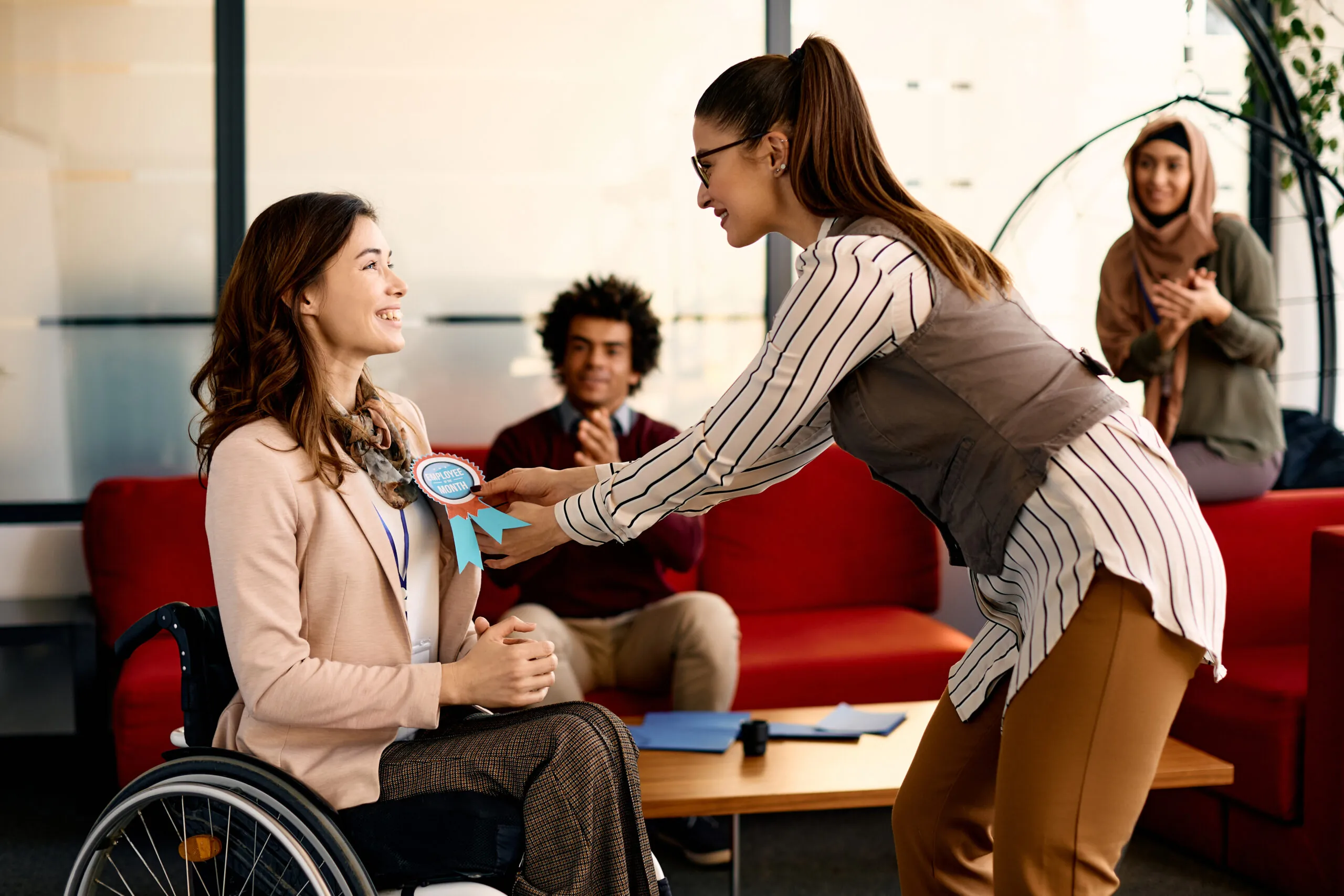 Happy disabled businesswoman receiving employee of the month badge in the office.